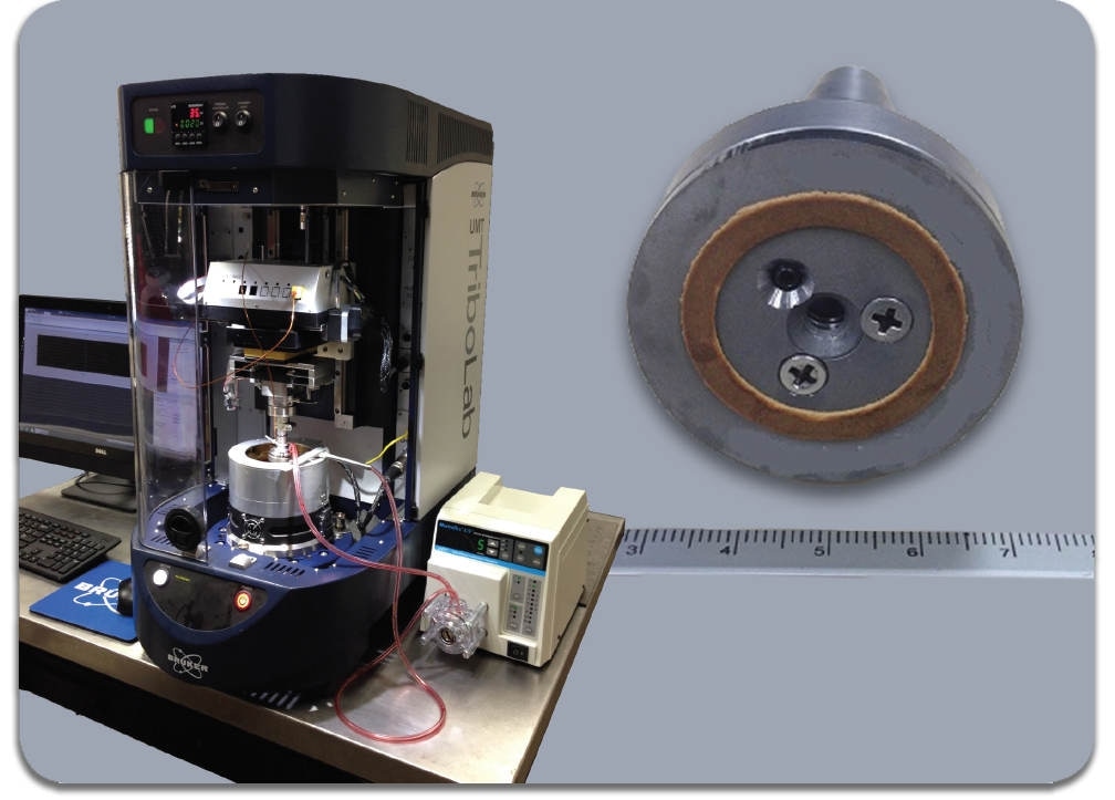 The UMT TriboLab benchtop tribotest system used in the simulation of clutch material testing, and detail of sub-scale clutch material sample (ruler in cm).