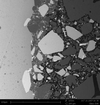 Image of a polished surface of glass (left) in contact with glass furnace construction material (right)