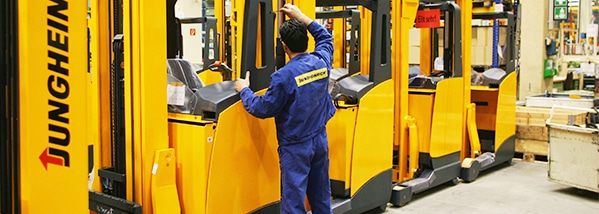 a man in a blue coat looking at a yellow machine