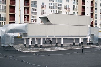 Air Handling Unit in metal box enclosure on rooftop of commercial building.
