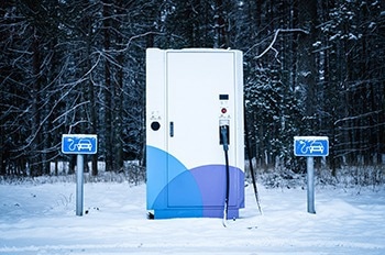 Snow-covered electric vehicle charging station during winter.