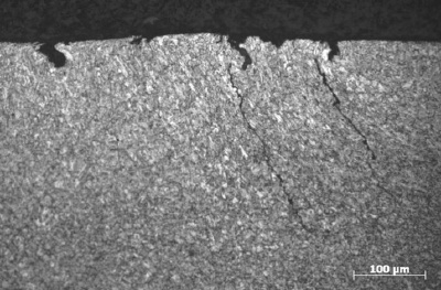 Photomicrograph of cracks initiating at pits in a cold-worked layer on the surface of a Grade P110 coupling.