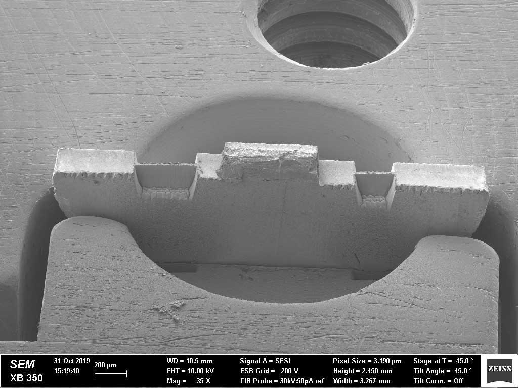 Engineering Materials. H-bar lamella preparation by fs-laser on a copper semi-circle grid. The left lamella is 400 μm wide, 215 μm deep and has a thickness of about 20 μm at the top. It was cut by the laser in 34 second. The amount of material that needs to be removed by FIB for final thinning is significantly reduced.