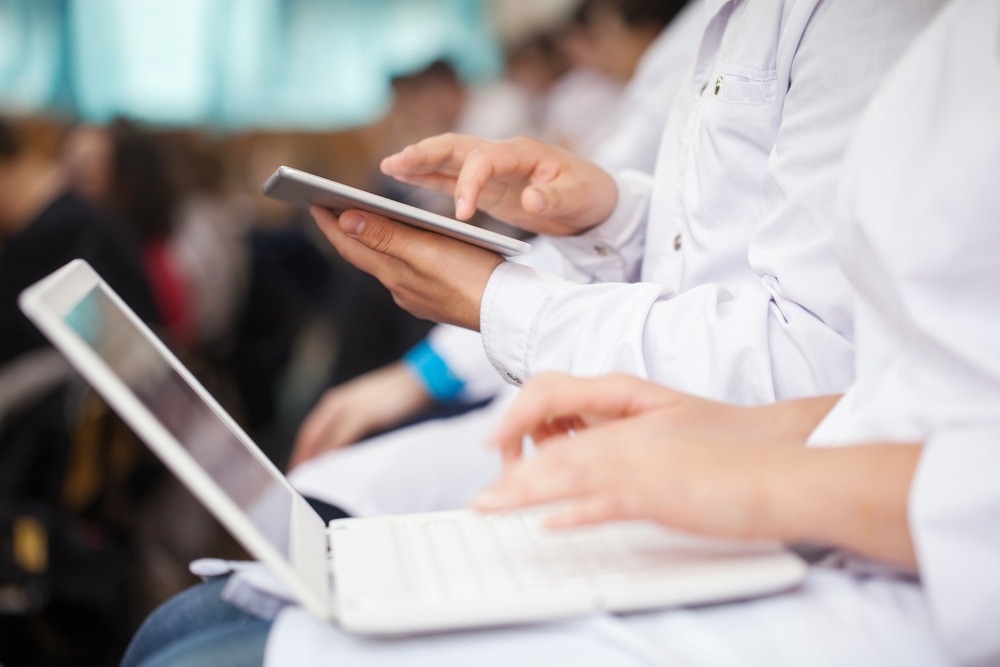 Male and female medical students or doctors using digital tablet and laptop during the lecture or conference.